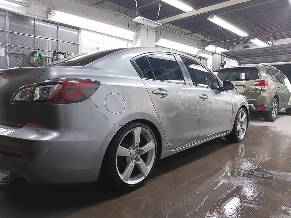 A silver sedan finished and parked inside the John Hall Body Shop bay.