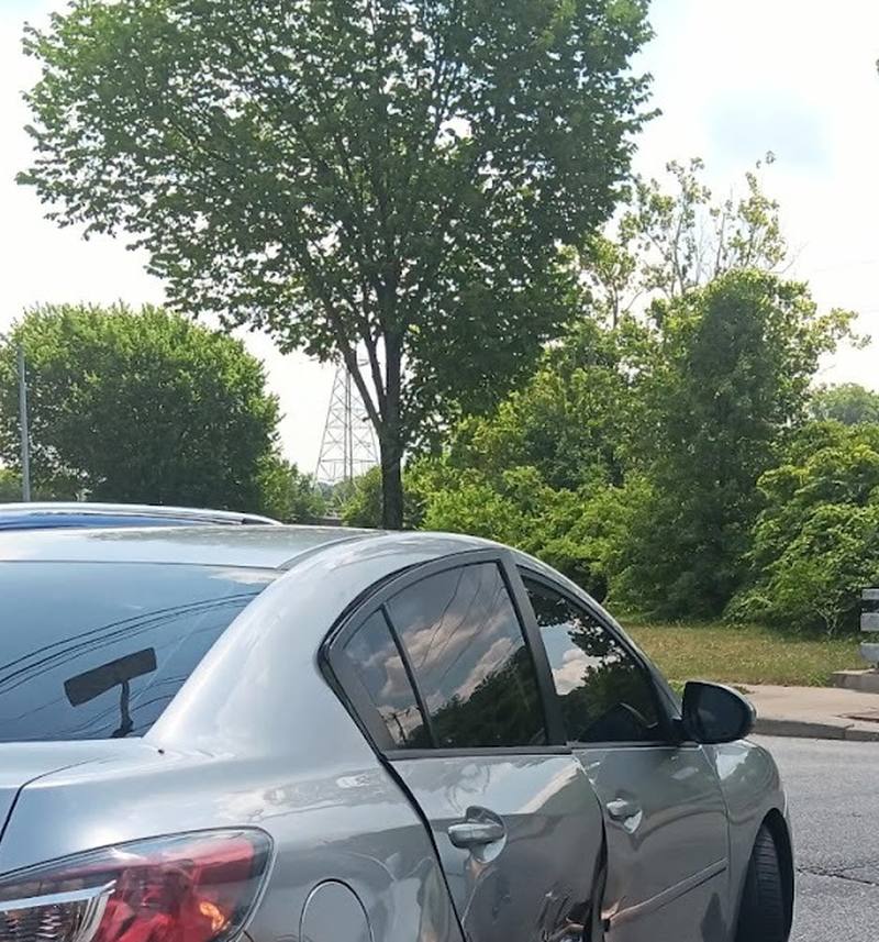 The creased rear quarter panel of a silver Mazda before repair.